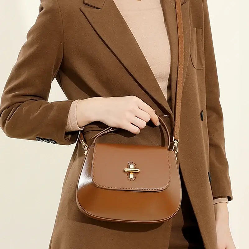 Elegant brown leather shoulder bag with decorative lock, perfect for casual and refined outfits.