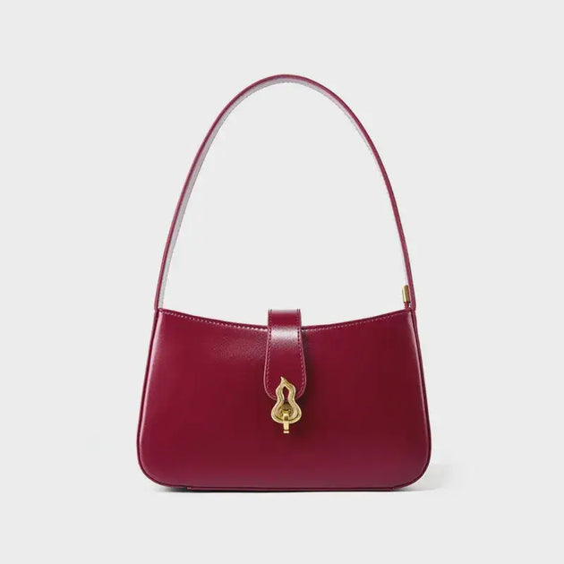 Burgundy leather shoulder bag with zipper closure and decorative lock, featuring a timeless half-moon silhouette.