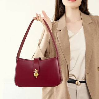 Red leather shoulder bag with zipper and decorative lock, perfect stylish accessory for any occasion.