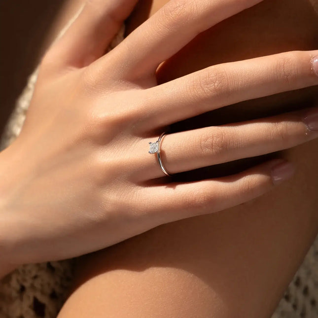 Emerald Cut Moissanite Ring on a woman's hand, showcasing its elegant design and sparkle in natural light.