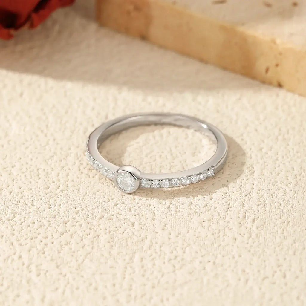 Geometric Bezel Moissanite Ring 925 Sterling Silver displayed on a textured surface with elegance and sparkle.