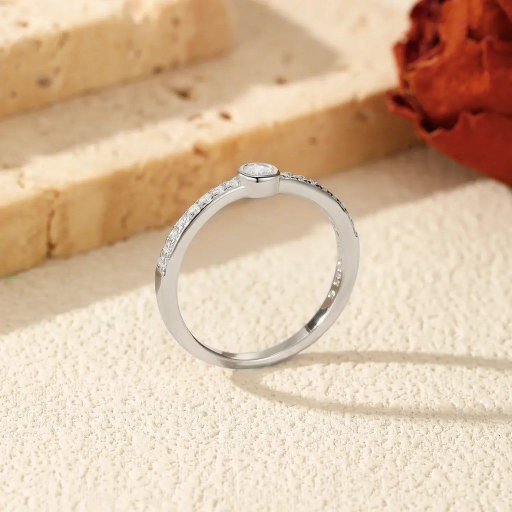 Geometric Bezel Moissanite Ring 925 Sterling Silver displayed on a textured surface with a warm background.