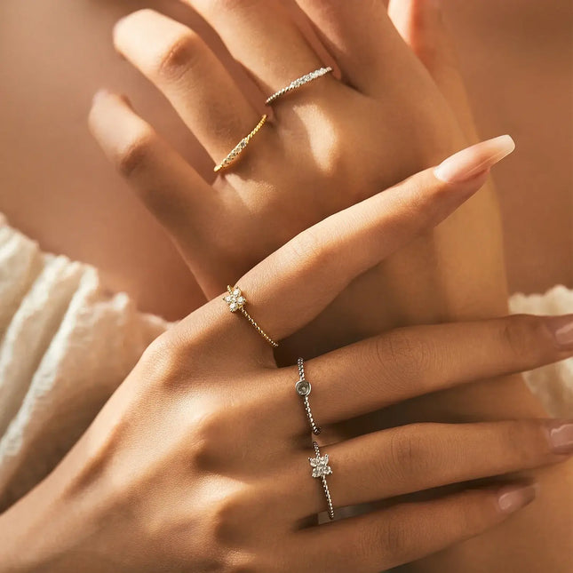Hands adorned with delicate rings, showcasing designs including a Geometric Cocktail Ring 925 Sterling Silver.