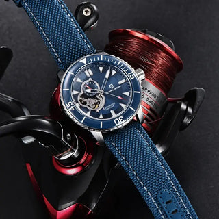 Mens Wristwatch waterproof with blue dial and nylon strap, placed beside a fishing reel.