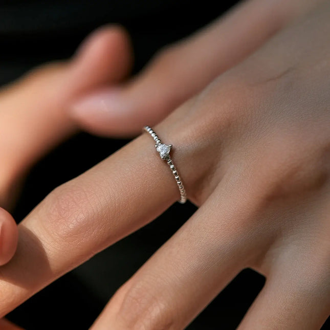 Close-up of a woman's hand wearing a Heart Moissanite Engagement Ring with a heart-shaped gemstone.