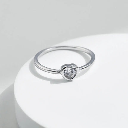 Heart shape Cut Moissanite Solitaire Wedding Ring on a white surface with smooth bezel setting.