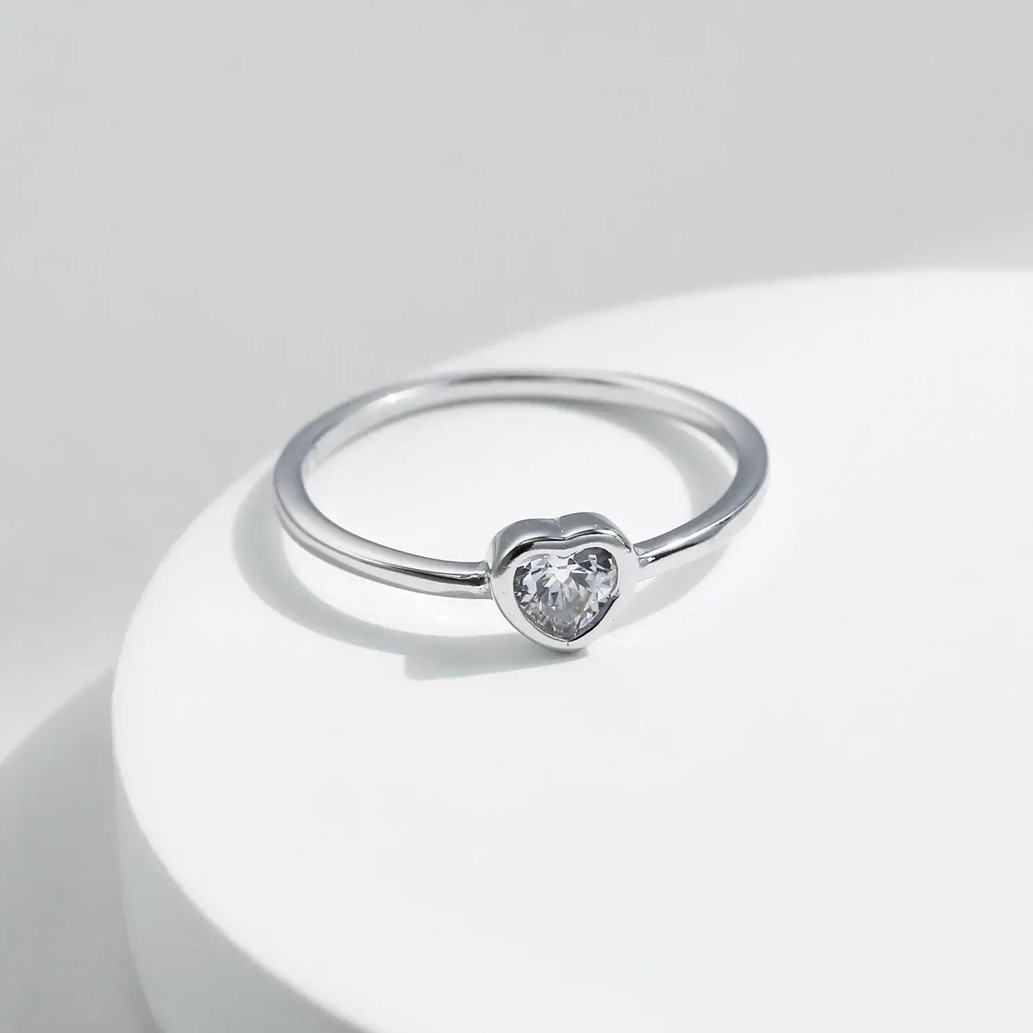 Heart shape Cut Moissanite Solitaire Wedding Ring on a white surface with smooth bezel setting.