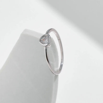 Heart shape Cut Moissanite Solitaire Wedding Ring on a smooth surface, showcasing the heart-shaped moissanite in a bezel setting.