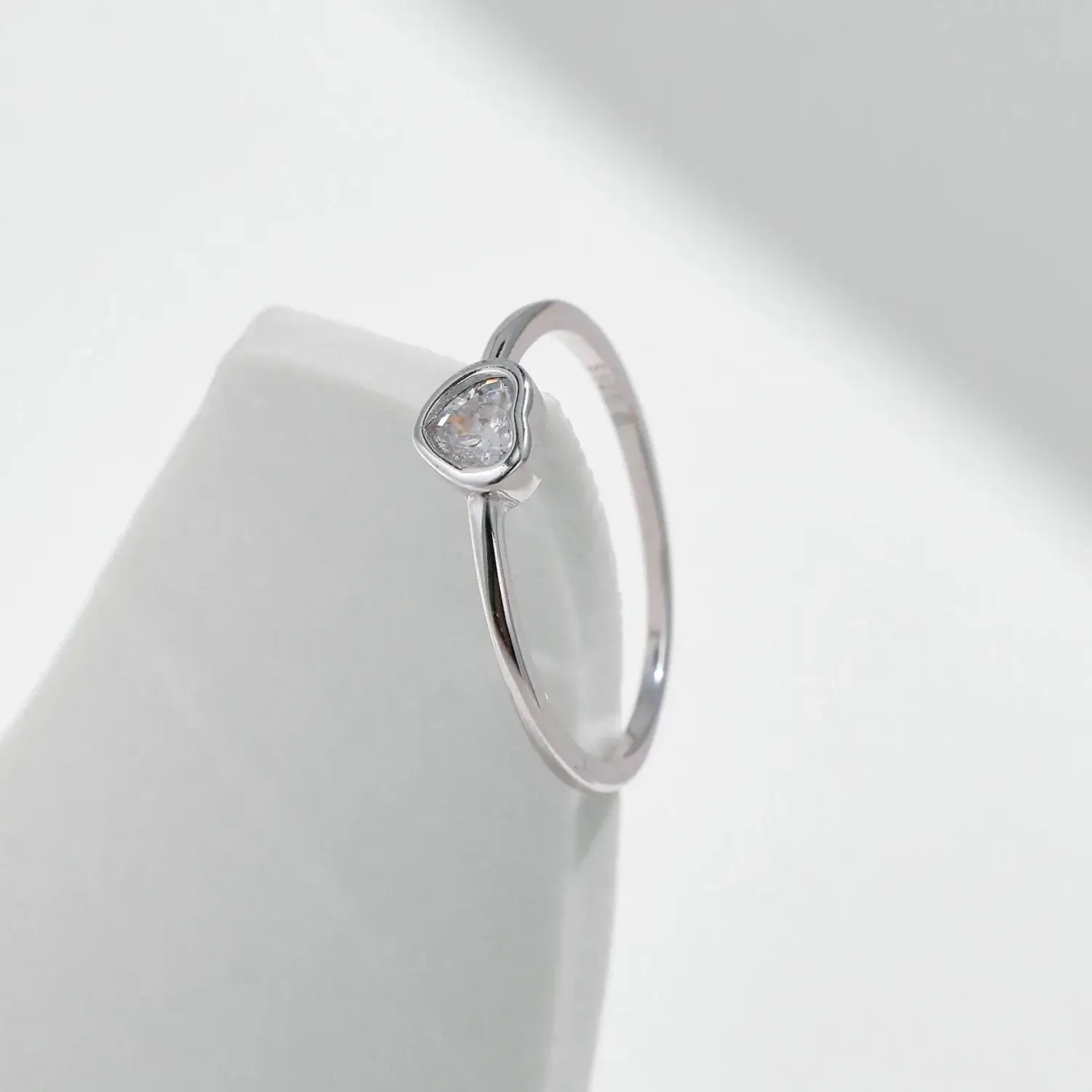 Heart shape Cut Moissanite Solitaire Wedding Ring on a smooth surface, showcasing the heart-shaped moissanite in a bezel setting.