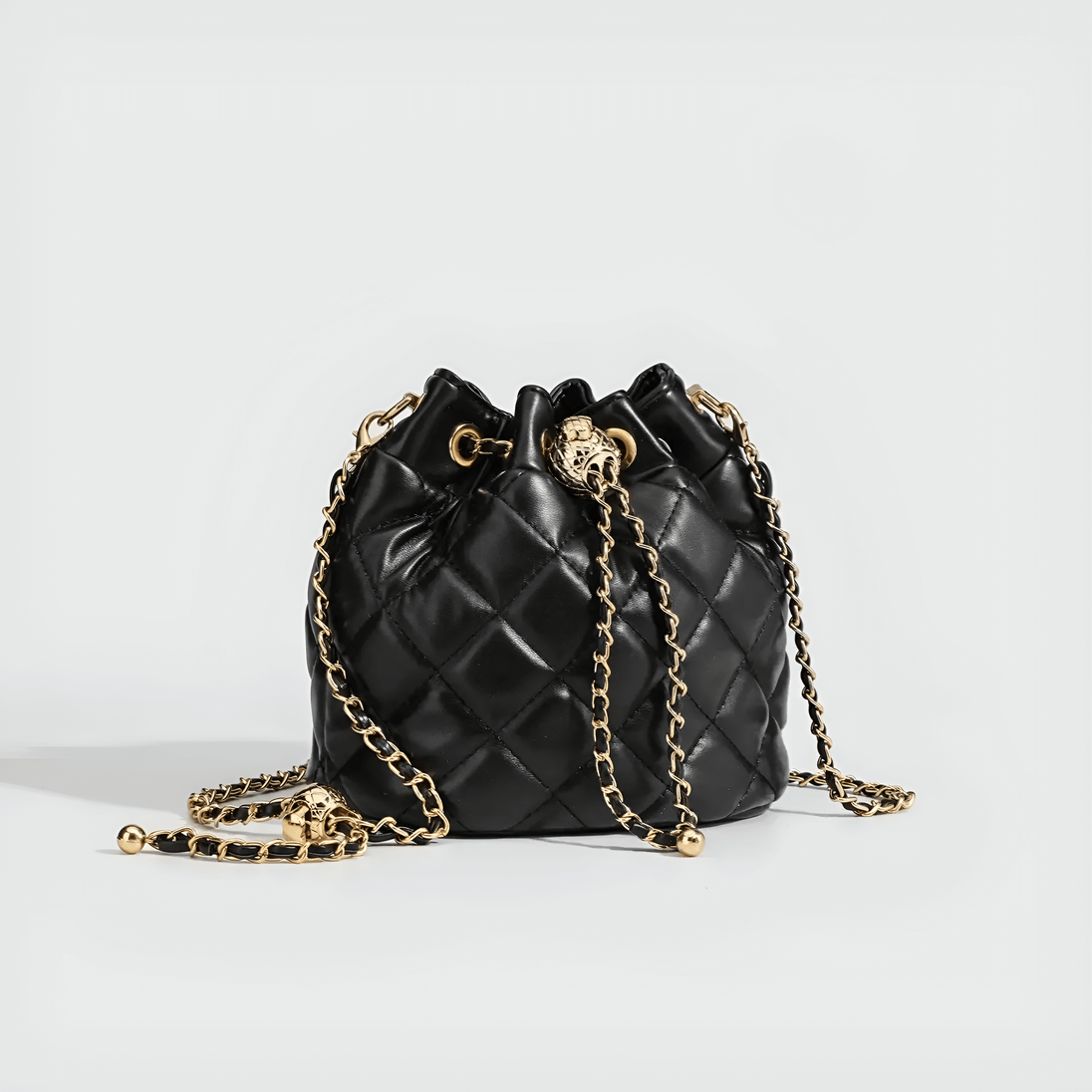 Minimalist black quilted drawstring bag with gold chain strap for chic everyday elegance.