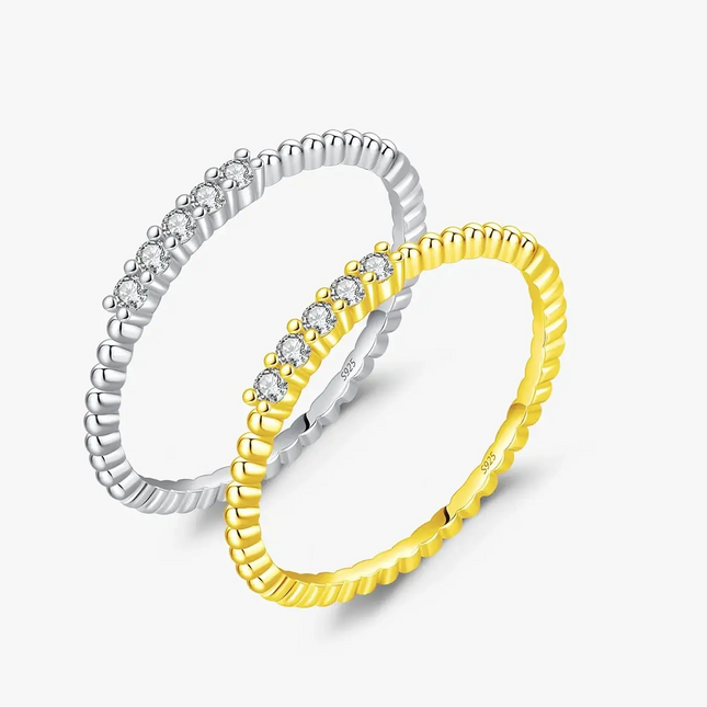 Moissanite Eternity Band Ring in 925 Sterling Silver next to a gold ring, showcasing sparkling stones.