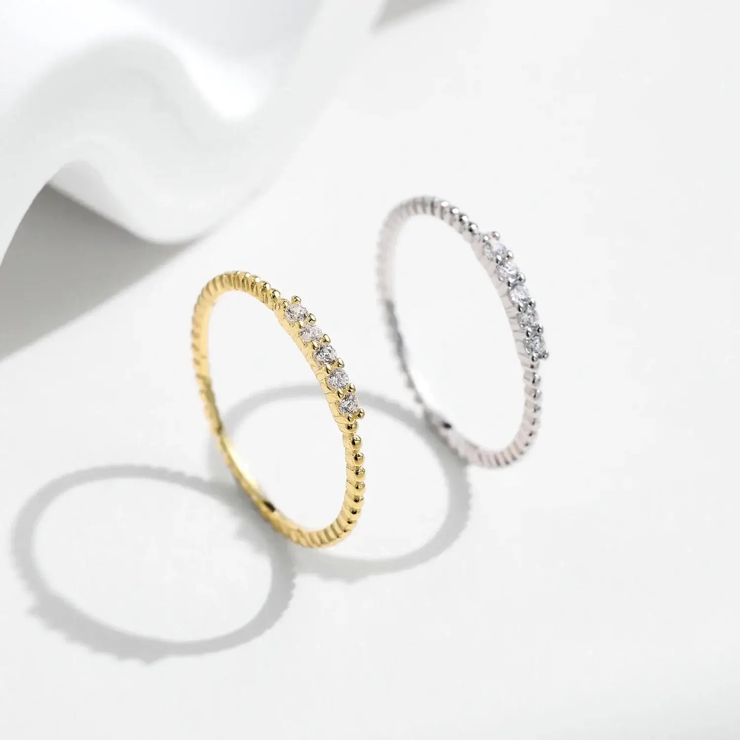 Moissanite Eternity Band Ring in 925 Sterling Silver displayed alongside a gold ring with multiple sparkling stones.