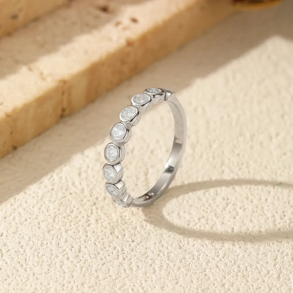 Round Moissanite Eternity Ring 925 Sterling Silver displayed on a textured surface.