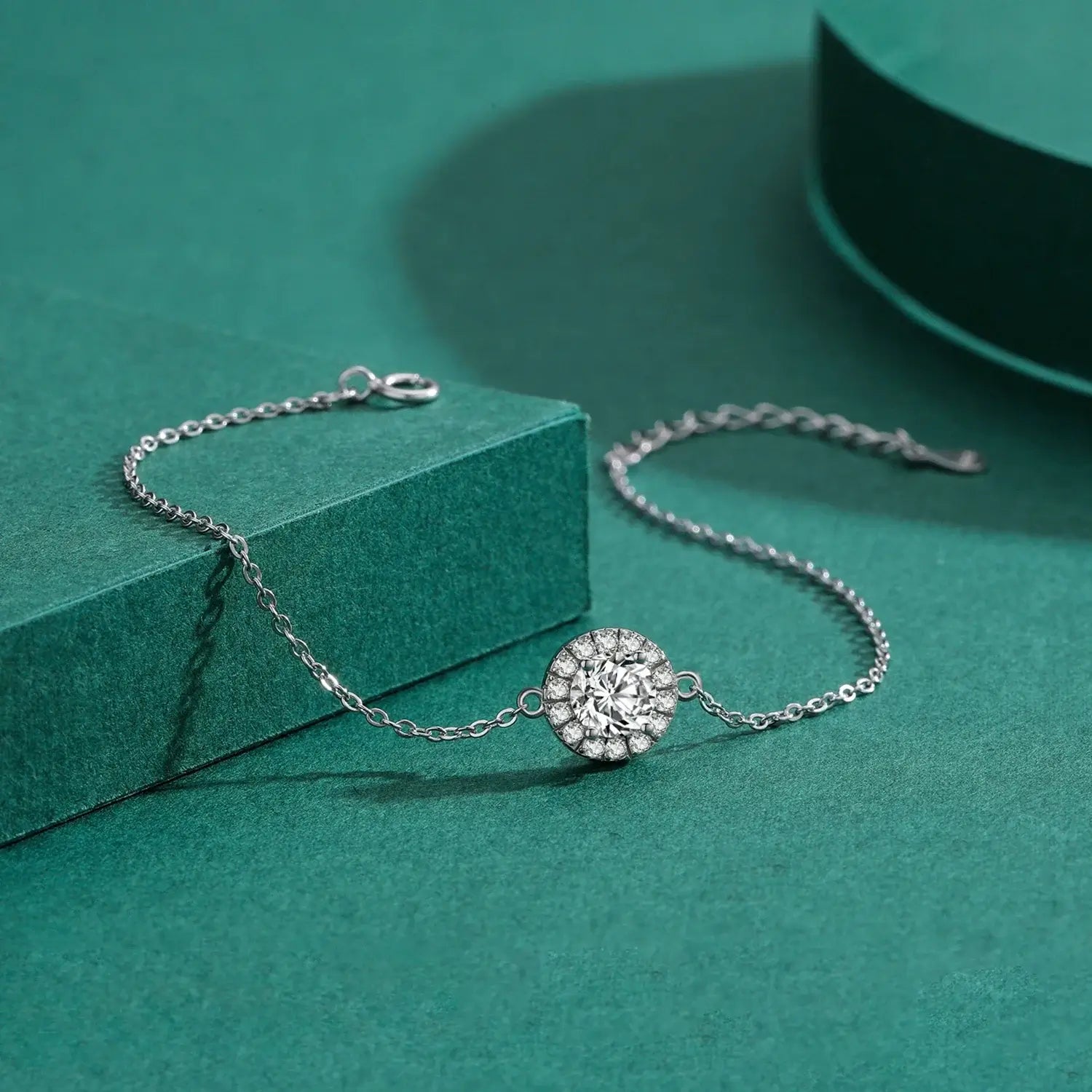 Round Zircon Charm Bracelet 925 Sterling Silver featuring a sparkling zircon main stone on a green background.