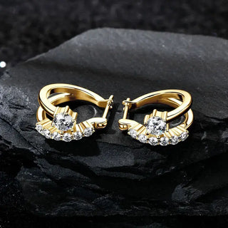Moissanite Diamond Round Earrings for Women in yellow gold with sparkling stones displayed on black rock.
