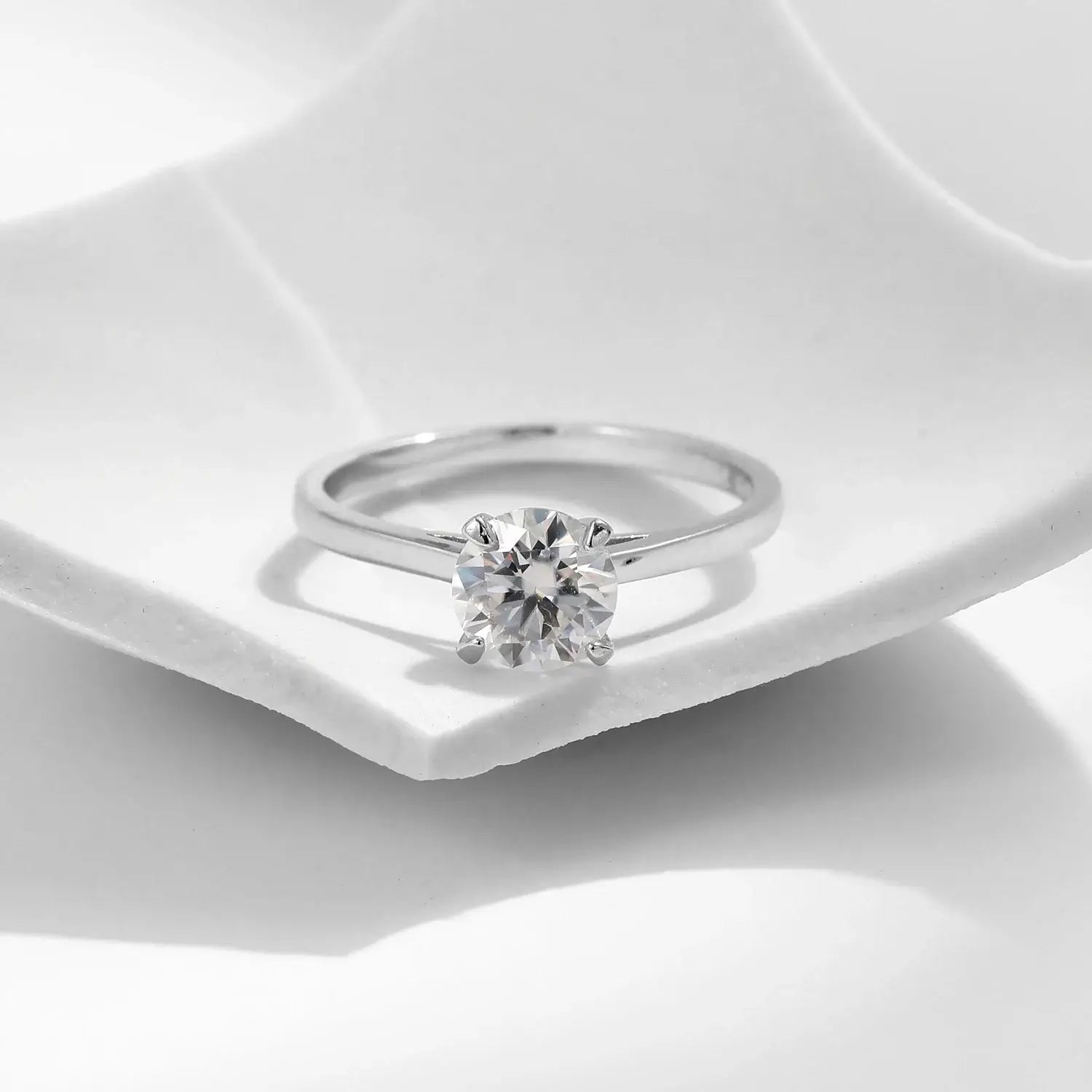 Round Moissanite Ring in 925 Sterling Silver displayed on a white plate, showcasing its brilliance and elegant prong setting.