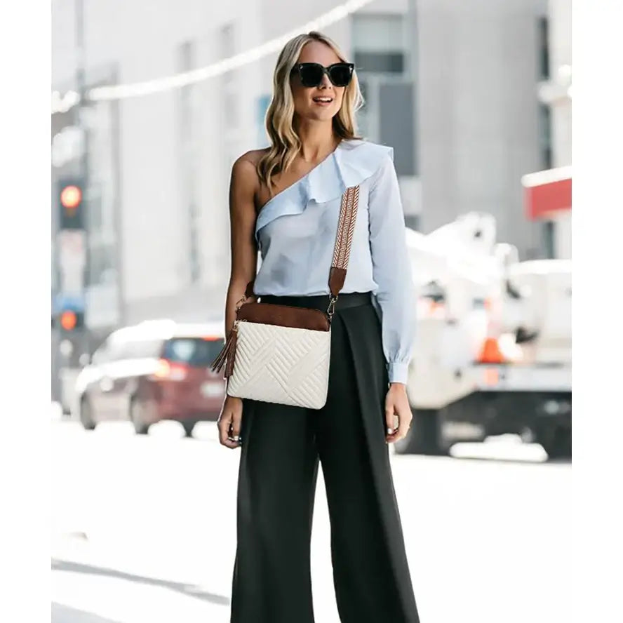 Fashionable woman wearing a blue blouse and black pants with a stylish PU Crossbody Bag on the street.