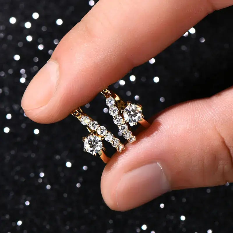 Moissanite Diamond Round Earrings for Women held between fingers on a sparkling background.