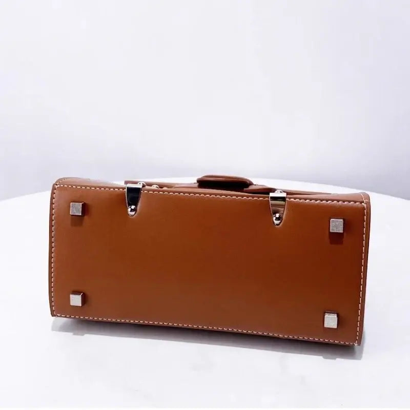 Handbag with wooden handle and rivet decoration, featuring a brown exterior and metal rivets on the bottom.