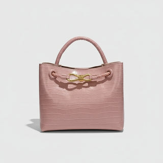 Women's Handbag in soft pink crocodile pattern with gold bow closure.
