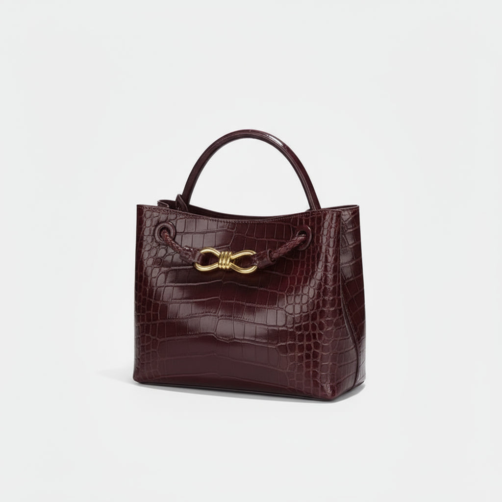Women's Handbag in burgundy crocodile pattern with gold closure.