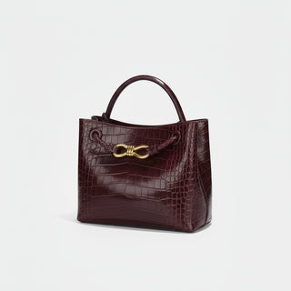 Women's Handbag in burgundy crocodile pattern with gold closure.