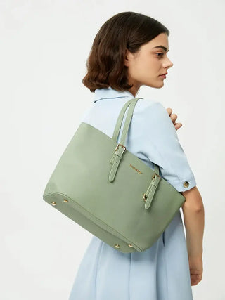 Woman holding a light green tote bag with adjustable shoulder straps, wearing a blue dress.