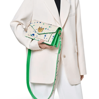 White women's crossbody bag with paint splatter design and gold fox emblem.