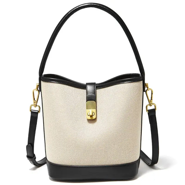 Beige and black women’s casual bucket bag with top handle and crossbody strap featuring gold lock detail.