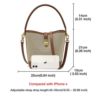 Beige and black women's bucket bag with top handle, crossbody strap, and gold lock detail; ideal for casual style.