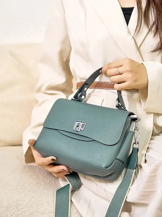 Crossbody bag in teal, structured and stylish for modern elegance, features silver lock detail and versatile straps.