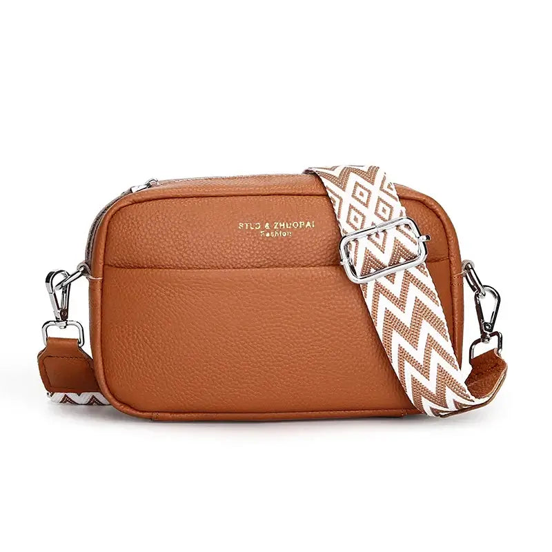 Brown genuine leather crossbody bag with geometric pattern strap and zipper closure.
