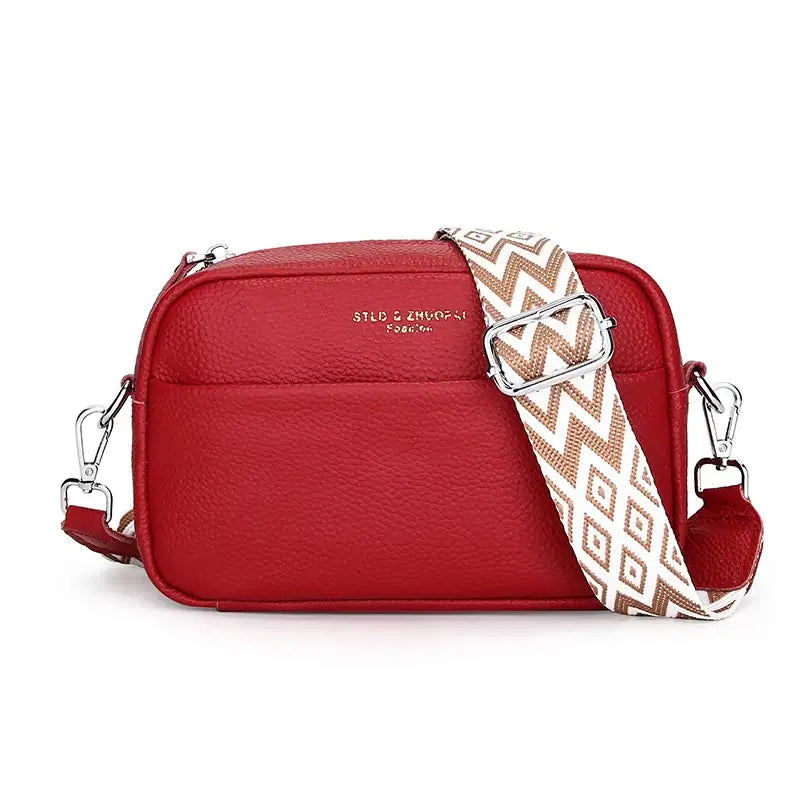 Red leather crossbody bag with adjustable geometric strap and zipper closure, perfect for trendy women's fashion.
