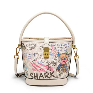 Trendy women's graffiti print bucket bag in beige with top handle and crossbody strap, unique cartoon design.