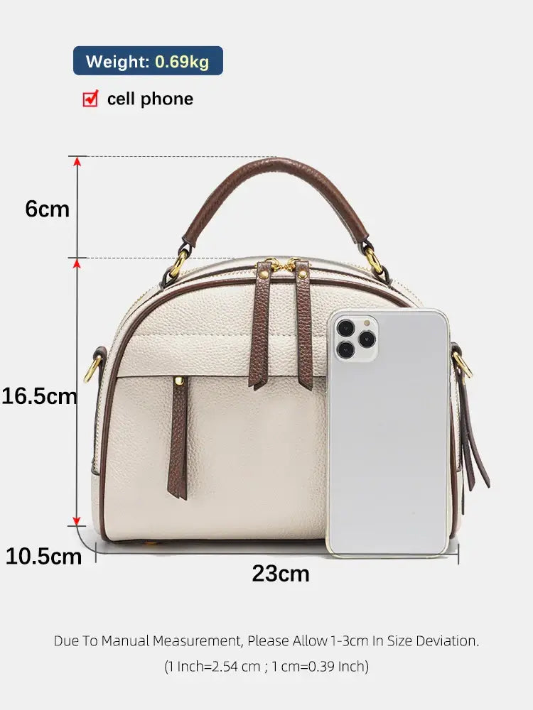 Structured beige leather shoulder bag with dimensions displayed next to a cell phone for size reference.