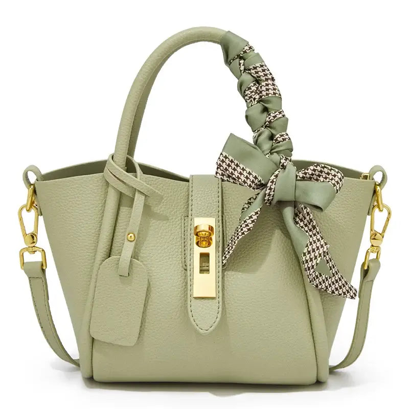 Light green leather handbag with gold lock and scarf handle detail, stylish hobo bag for women.
