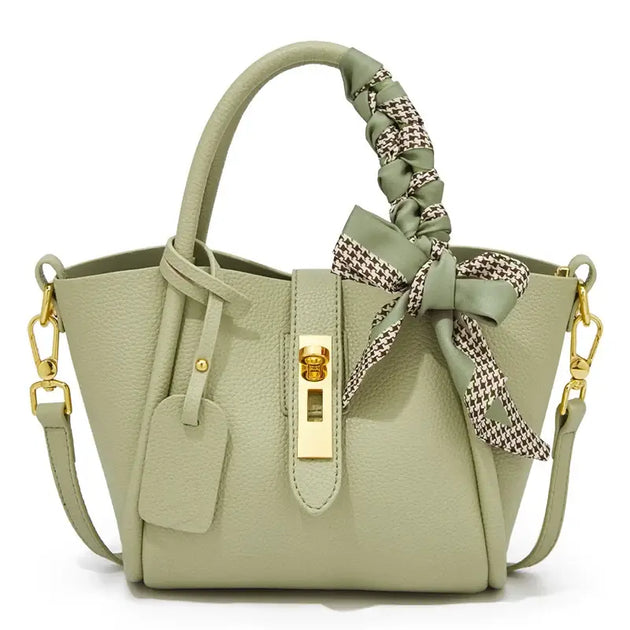 Light green leather handbag with gold lock and scarf handle detail, stylish hobo bag for women.