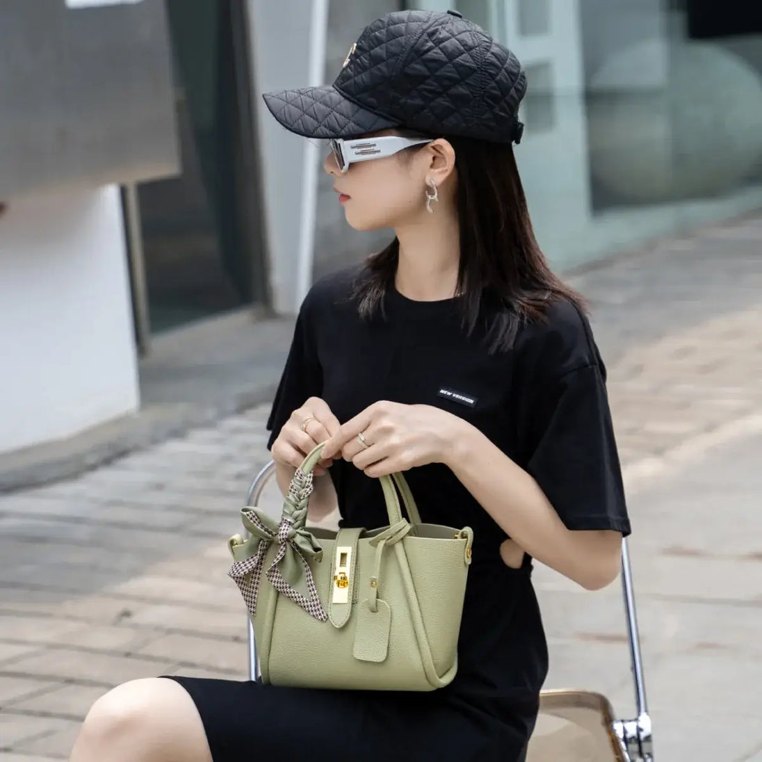 Light green leather women’s handbag with gold lock, scarf handle detail, vintage style.