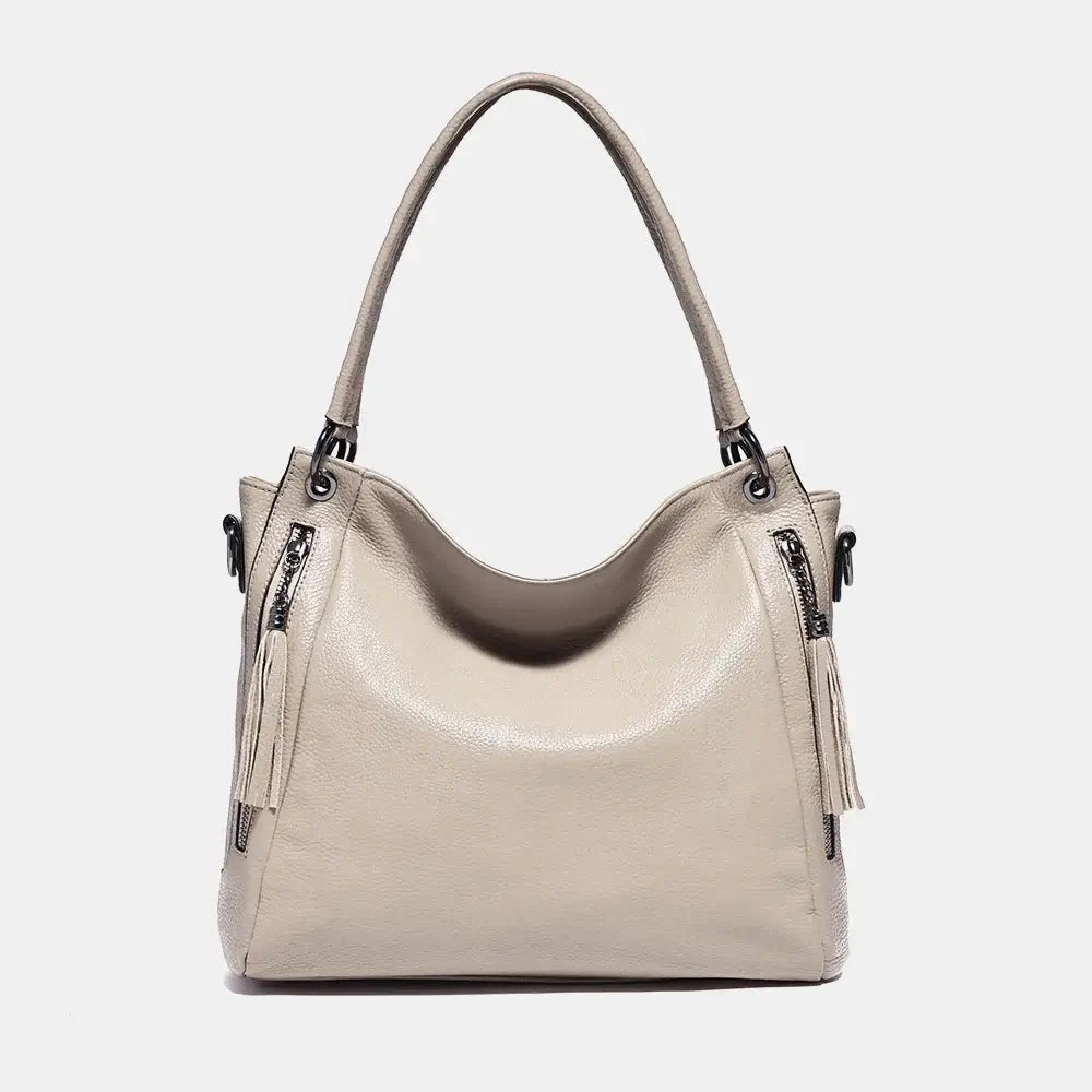 Shoulder hobo bag in soft beige leather, stylish design, spacious with dual straps and tassel detail.