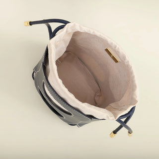 Hollow-out bucket bag interior view, elegant design, summer accessory, canvas lining, drawstring closure.