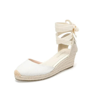Espadrille sandals in cream color, featuring cross-strap design and wedge heel for casual summer wear.