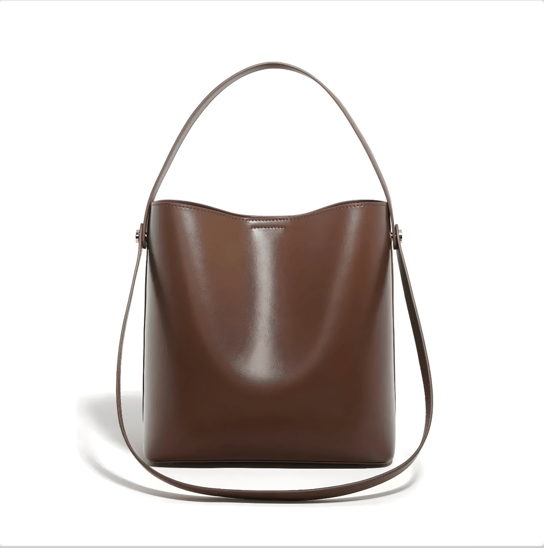 Women's brown leather shoulder bag with top handle and crossbody strap, soft minimalist design, spacious interior.
