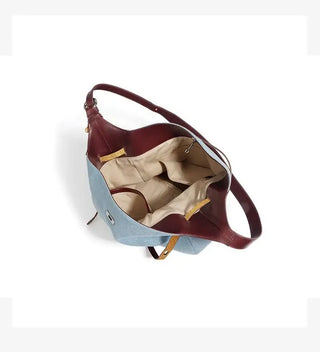 Casual women’s shoulder bag in light blue with brown leather strap, showcasing interior pockets and sleek design.
