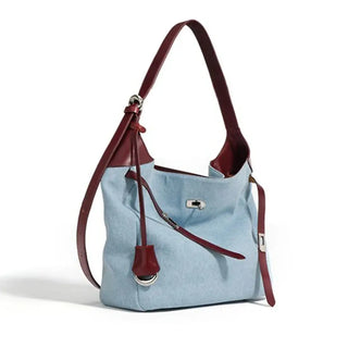 Casual light blue denim women’s shoulder bag with brown leather strap, stylish bucket tote for everyday use.