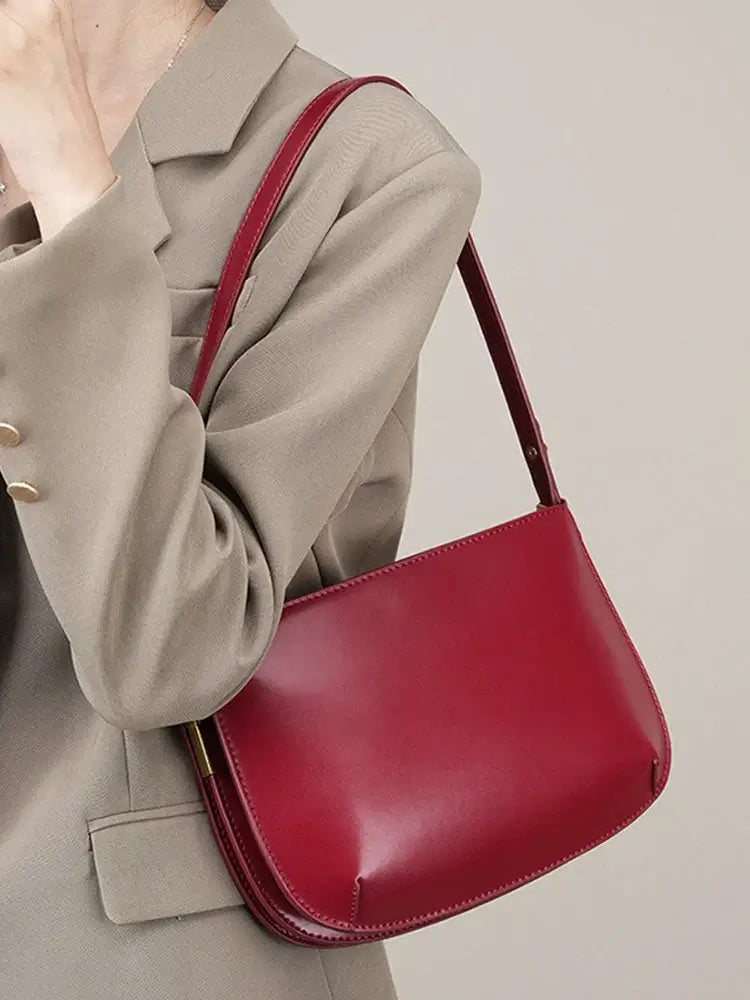 Luxurious red shoulder bag made of genuine leather, featuring a sleek design and stylish ruched texture.