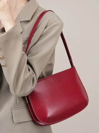 Luxurious red shoulder bag made of genuine leather, featuring a sleek design and stylish ruched texture.