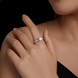 Women's silver engagement ring featuring a sparkling round cut crystal, elegantly displayed on a hand.