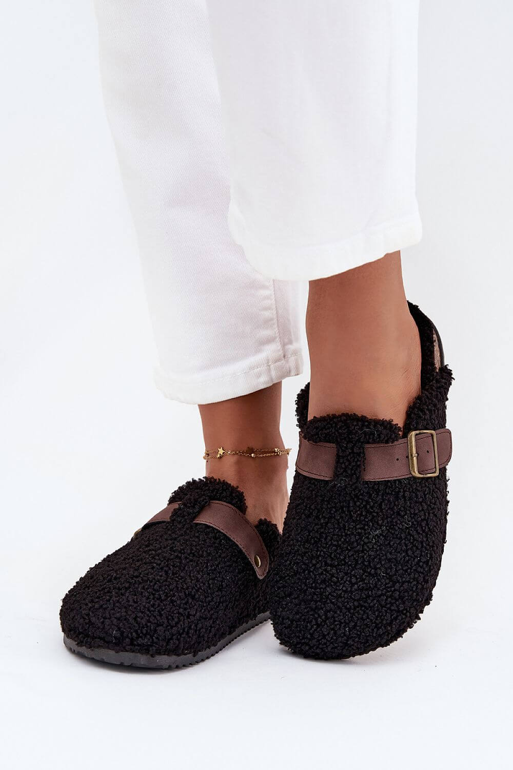 Women's sheepskin-style slippers featuring a soft black exterior and adjustable strap for comfort and style.