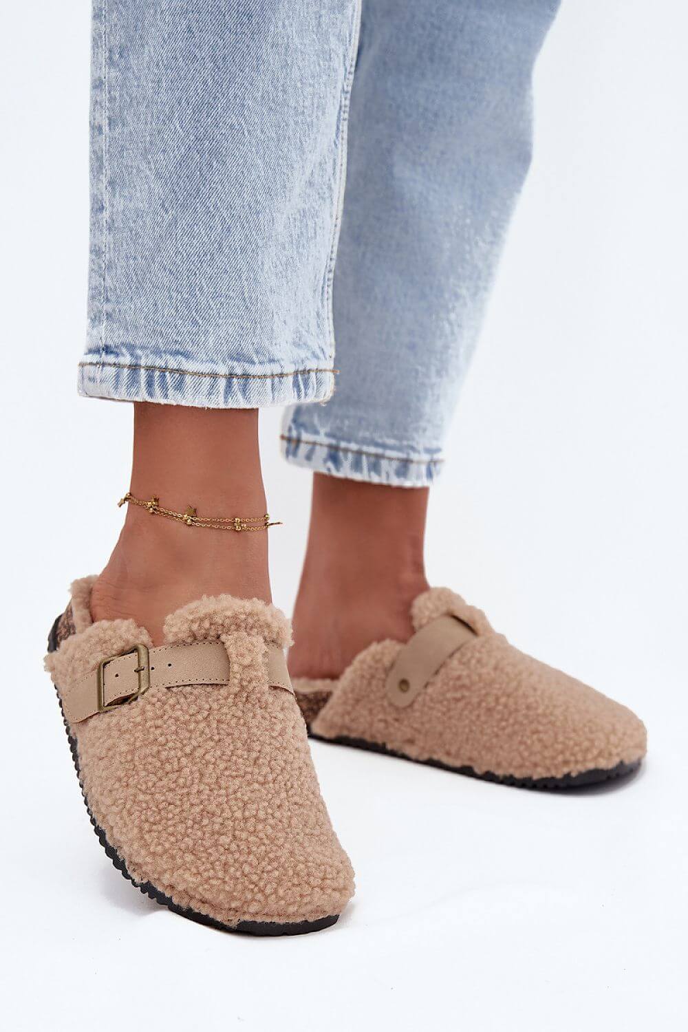 Woman wearing women's sheepskin-style slippers with adjustable strap and soft lining, styled with casual jeans.