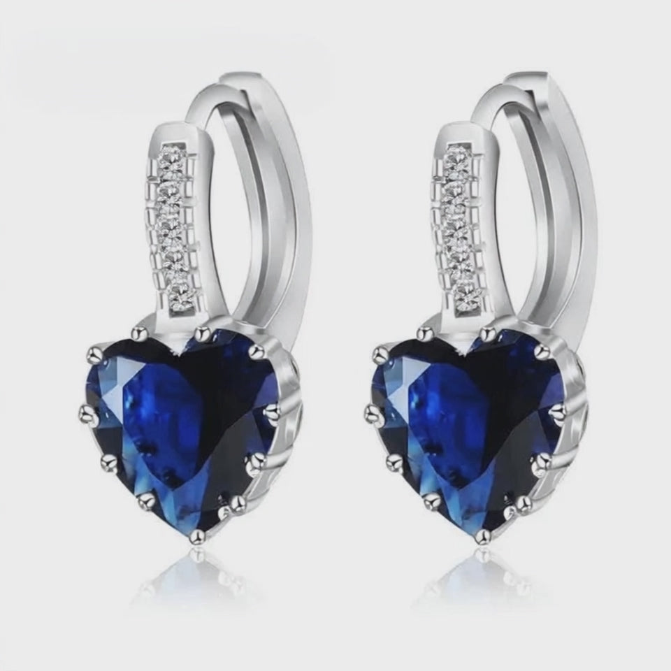 Sterling Silver Crystal Drop Earrings featuring heart-shaped blue gemstones and sparkling accents. Trendy and stylish design.